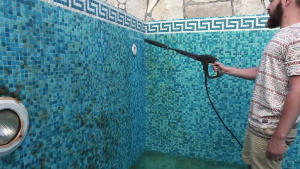 Un hombre está limpiando la pared de la piscina — Vídeo de stock