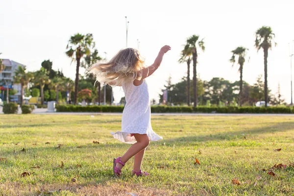 Little girl fun rides and jumps on the lawn — Stock fotografie