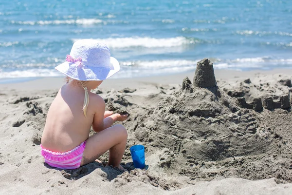 Jeune femme construit un château de sable — Photo