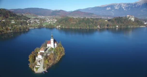 Vista aérea de la iglesia de San Martín en la isla y el paisaje del lago Bled con montaña — Vídeos de Stock