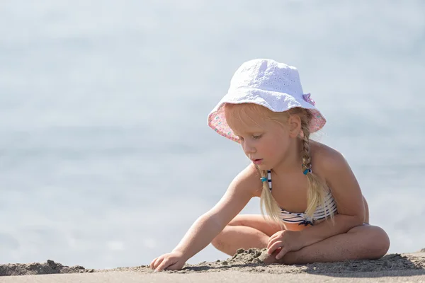 Klein meisje zittend op het strand. — Stockfoto