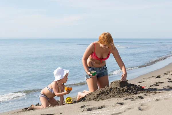 Мама і дочка будівництво замку піску — стокове фото