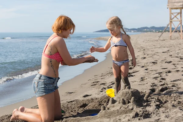 Mamá y su hija están construyendo un castillo de arena —  Fotos de Stock