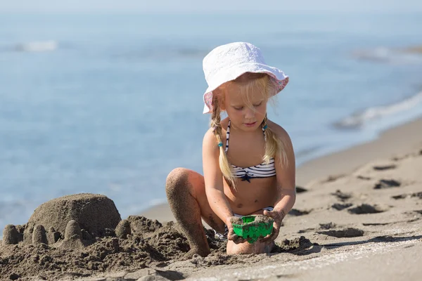 Meisje, bouw een zandkasteel op het strand — Stockfoto