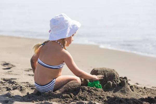 Chica construyendo un castillo de arena en la playa —  Fotos de Stock