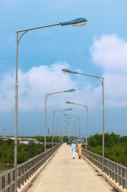 İskele ya da iskele, yaya yolu gezinti güvertesi ve gün doğumunda deniz. Arka plan için iskelenin güzel manzarası. Jetty 'yi geçen turist..