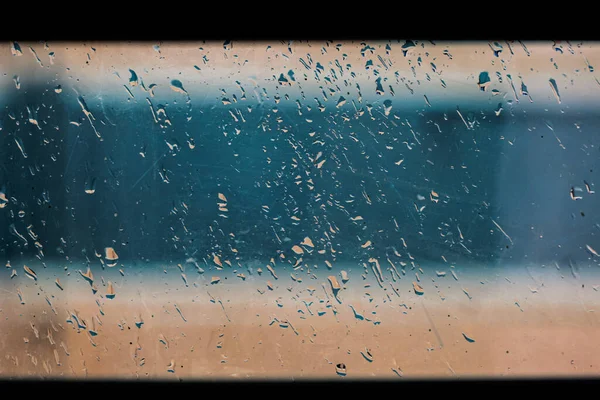 Drops of rain on the blue glass background. drops on glass after rain for wallpaper. Drops on glass, window condensation, and the background for text.