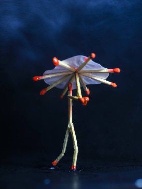 Yağmurda kibrit çöpü şemsiyeli bir adam. Yağmur konsepti. Kibrit çöpü sanat fotoğrafçılığı karakteri oluşturmak için kibrit çöpleri kullanır.