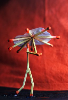 Yağmurda kibrit çöpü şemsiyeli bir adam. Yağmur konsepti. Kibrit çöpü sanat fotoğrafçılığı karakteri oluşturmak için kibrit çöpleri kullanır.