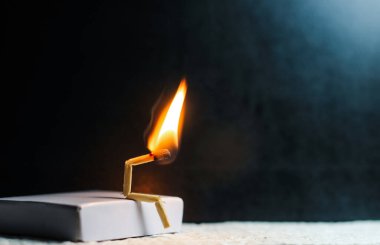 Zayıflık, üzüntü ve yalnızlık kavramı. İnsan yapımı kibrit çöpü. Yanan kibrit çöpü adam ortağın olmadan tek başına oturuyor. Kibrit kutusu sanat fotoğrafçılığı.