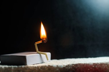 Zayıflık, üzüntü ve yalnızlık kavramı. İnsan yapımı kibrit çöpü. Yanan kibrit çöpü adam ortağın olmadan tek başına oturuyor. Kibrit kutusu sanat fotoğrafçılığı.