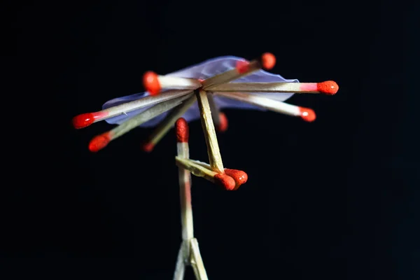 A matchstick man with a matchstick umbrella in the rain. Raining concept. Matchstick art photography used matchsticks to create the character.