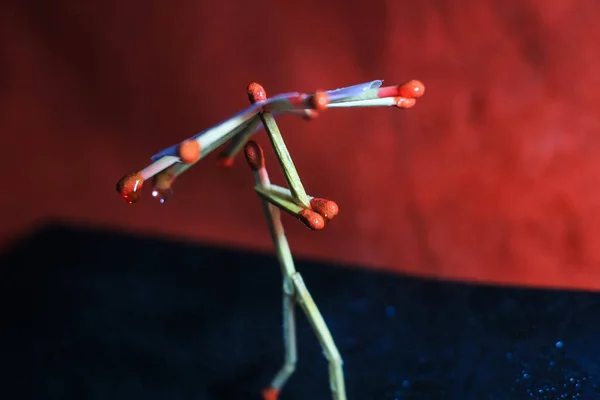 A matchstick man with a matchstick umbrella in the rain. Raining concept. Matchstick art photography used matchsticks to create the character.