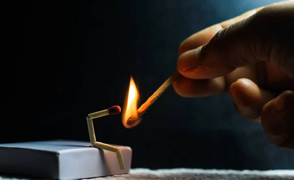 Zayıflık, üzüntü ve yalnızlık kavramı. İnsan yapımı kibrit çöpü. Yanan kibrit çöpü adam ortağın olmadan tek başına oturuyor. Kibrit kutusu sanat fotoğrafçılığı.