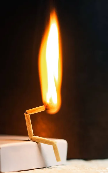 Concept of weakness, sadness, and loneliness. Image of a man-made matchstick. Burning matchstick man sitting alone without a partner. Matchstick art photography.