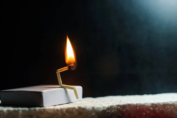 Zayıflık, üzüntü ve yalnızlık kavramı. İnsan yapımı kibrit çöpü. Yanan kibrit çöpü adam ortağın olmadan tek başına oturuyor. Kibrit kutusu sanat fotoğrafçılığı.