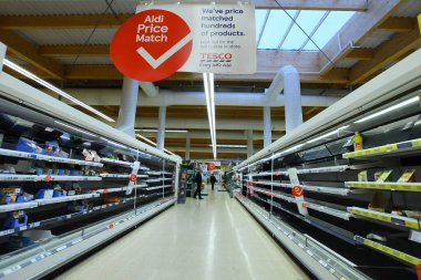 COVID-19 panik satın alımının sebep olduğu İngiltere 'deki bir süpermarkette boş raflar.