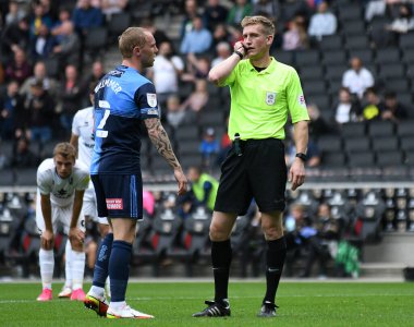 MILTON KEYNES, ENGLAND - SEPTEMBER 25, 2021: İngiliz hakem Scott Oldham (R) tarafından MK Dons FC ve Wycombe arasında oynanan 2021 / 22 SkyBet EFL Ligi 'nin 9 haftalık maçına ev sahiplerine ceza verilmesi üzerine Dons' dan Tennai Rosharne Watson (L) protestoları