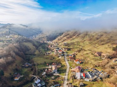 Romanya 'nın Brasov ilçesindeki Moeciu de Jos köyünün sonbahar sonlarında Karpat Dağları tarafından çevrelenmiş insansız hava aracı görüntüsü.