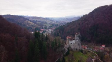 Romanya 'nın Brasov ilinin Bran kenti yakınlarındaki ormanlık tepelere bakan Bran Şatosu' nun insansız hava aracı görüntüleri. Kışın erken saatlerinde esir alınmış, tarihi kaleyi ve çevresindeki manzarayı gösteriyor..