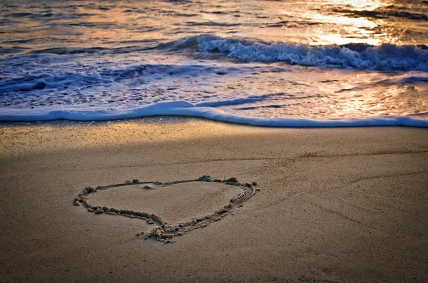 Een hart op het strand bij zonsondergang — Stockfoto