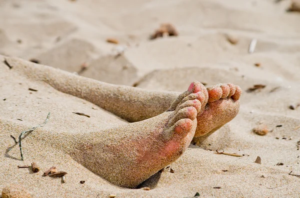 Onder de zon twee voeten uit uit het warme zand — Stockfoto