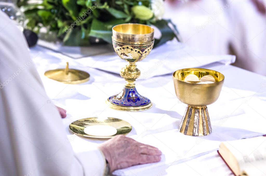 hand of the pope with consecrated host that becomes the body of jesus christ and chalice for wine, blood of christ, in the churches of rome and all over the world