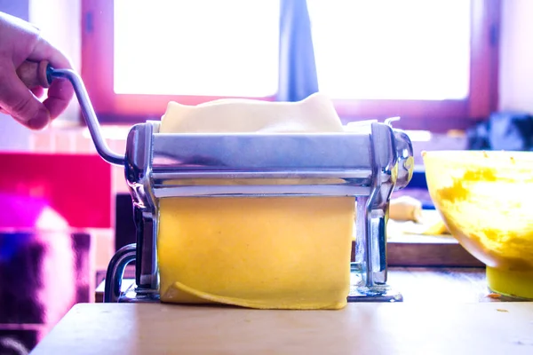 伝統的な手動シーターを持つイタリアの主婦は パーティーのランチのために小麦粉 塩で作られたイタリアの太陽の色である卵パスタを転がします — ストック写真
