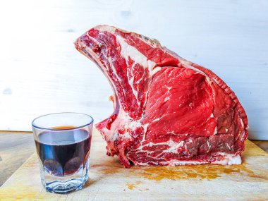 Kemiğe sığır eti, olgunlaşmış, barbekü ve öğle yemeği için hazır, Floransa bifteği, yanında da bir bardak gerçek kırmızı şarap.