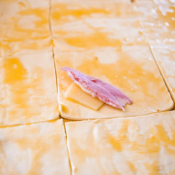 preparation of home-made savory snacks with puff pastry, mortadella, cheese and egg, cooked in the oven