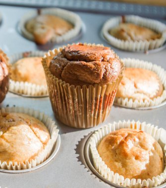 Sabah güneşi küçük kremalı ve çikolatalı kekleri aydınlatır, sıcak ve buharlı, fırından yeni çıkmış, kahvaltıya hazır.