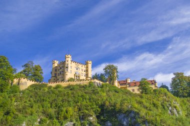 Hohenschwangau, ünlü ortaçağ şatosu, ejderhalarla, şövalyelerle ve prenseslerle, mavi göllerin karanlık ormanlarının arka planına karşı.