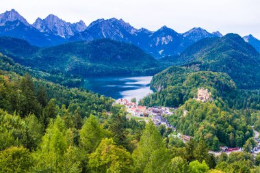 Hohenschwangau, ünlü ortaçağ şatosu, ejderhalarla, şövalyelerle ve prenseslerle, mavi göllerin karanlık ormanlarının arka planına karşı.