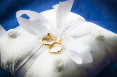 Beyaz ve yumuşak bir yastıktaki alyanslar güzel ve güzel kokulu çiçeklerle, aşkın sembolü sonsuza dek 