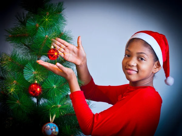 黒い少女はクリスマス ツリーを飾る ストックフォト