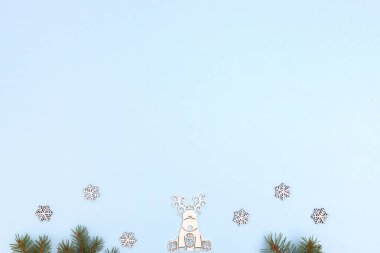 Oyuncak tahta geyik ve kar taneleri, mavi arka planda çam dalları. Kartpostal şablonu. Yeni yıl, kopyalama alanı