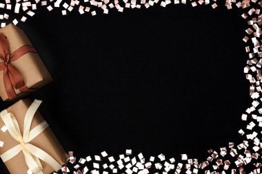 Kurdeleli iki hediye ve siyah arka planda altın konfeti. Tatil konsepti, kopyalama alanı.