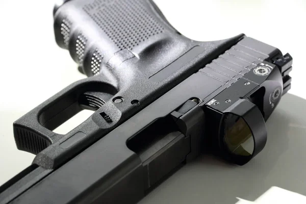Beyaz arka planda 9 mm 'lik bir tabancanın yakın çekimi. Kırmızı nokta görüşlü bir tabanca. Glock 19.