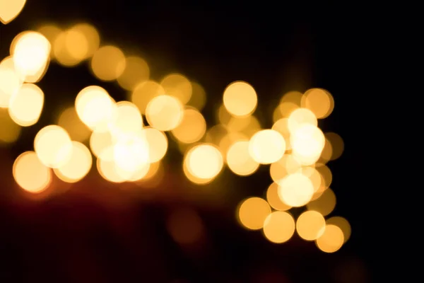 Karanlıkta parlayan sarı ışıkların soyut arkaplanı. Bokeh etkisi.