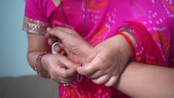 Donna indiana che indossa rosa Saree cravatte un colorato braccialetto di perline su un altro polso Womans - Primo piano girato — Video Stock