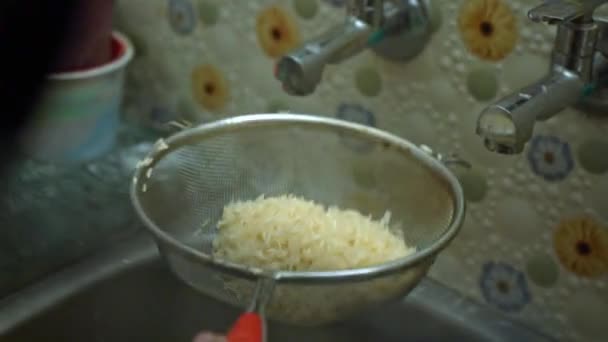 Filtrando água de grãos de arroz lavados na pia da cozinha com um filtro. de perto — Vídeo de Stock