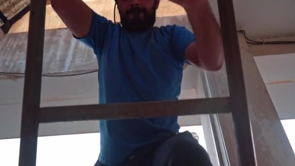 Vista di un uomo che sale su una scala d'acciaio all'interno di un edificio incompiuto. angolo basso, inseguimento colpo — Video Stock