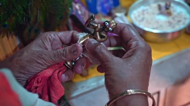Weibliche Hände wickeln die Figur von Lord Krishna während der Janmashtami-Feier in Indien ein. Nahaufnahme, Zeitlupe — Stockvideo