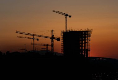 Zaragoza 'da gün batımında yapım aşamasındaki bir binanın vinçlerinin silueti.