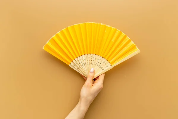 Hand holding hand fan made of bamboo and paper