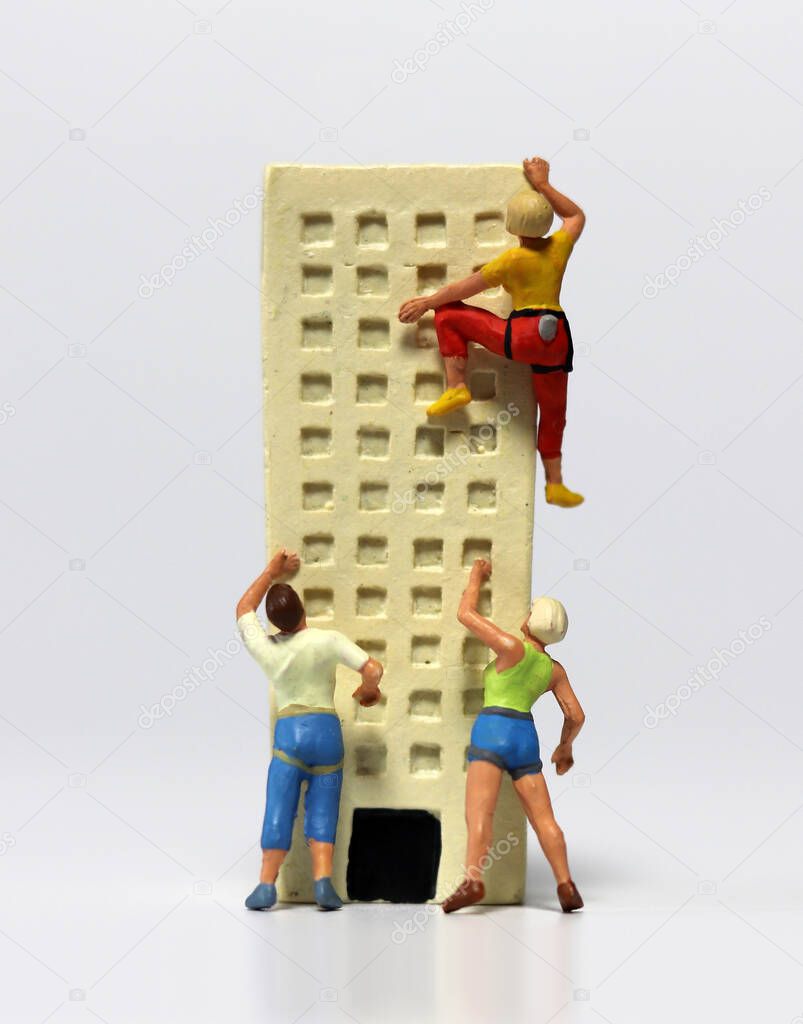 Miniature people trying to climb a miniature building. The concept of deepening job shortages.