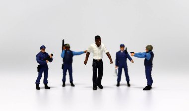 Siyah bir minyatür adamı çevreleyen polis minyatürleri. Irksal ayrımcılık kavramı.