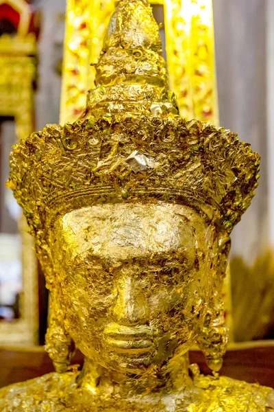 Closeup gold leaf on the face buddha statue