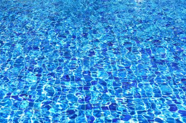 Kiremit kaplı zeminde parlak ışık yansımaları olan berrak mavi yüzme havuzu su yüzeyi. Yaz arkaplanını dalgalar ve nazik dalgalarla ferahlatıyor. Üst manzara, parlak ve canlı.