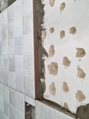 Banyo tadilatı sırasında duvarı gri seramik fayanslarla kaplamak. Kurulum sürecinin yakın çekimi beton yüzeyde yapışkan havan topu gösteriyor. Profesyonel ev geliştirme inşaat sahnesi